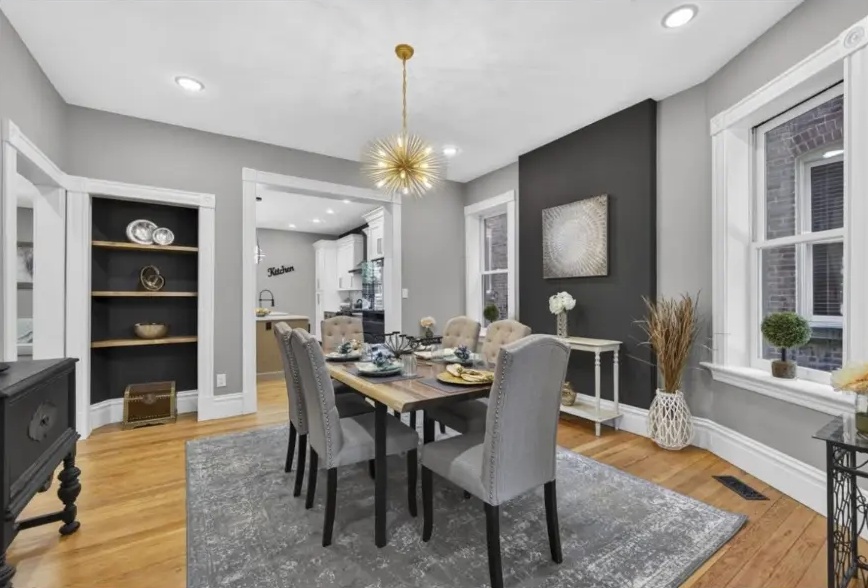 Dining room with built-in shelving, dark accent wall and pendant light