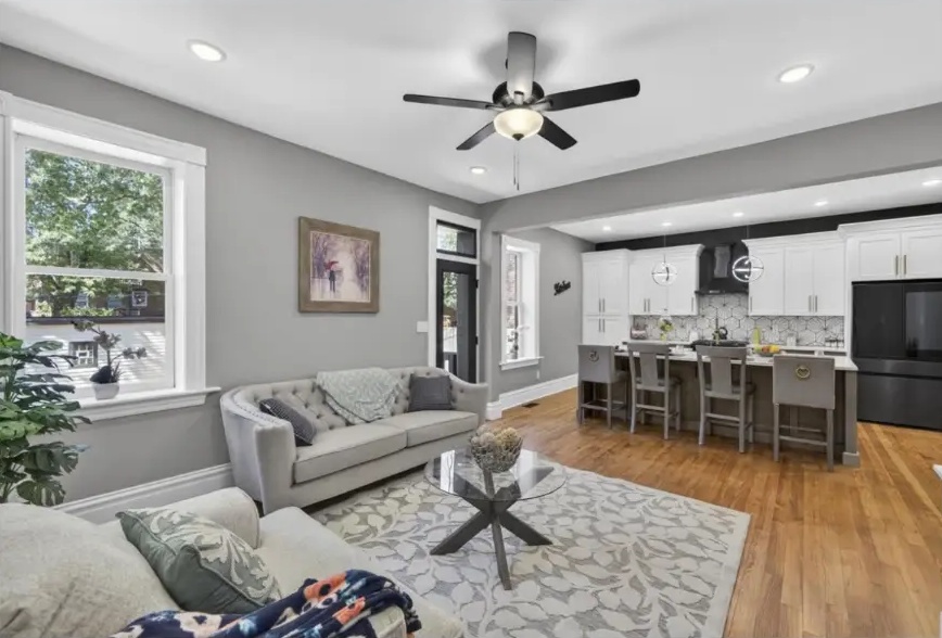 Living area with pale sofas and large windows opening into the kitchen
