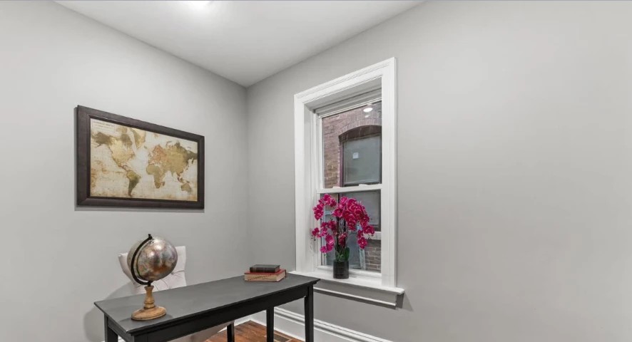 Small office with black writing desk, globe, framed map and white-trimmed window