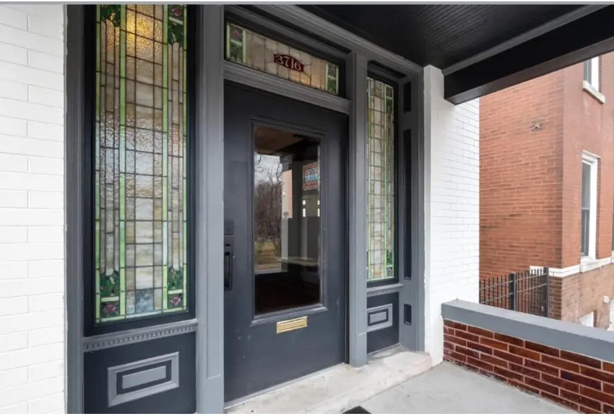 Front entry with dark glazed door, stained glass sidelights and transom window