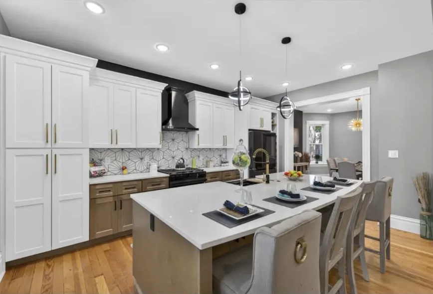 Kitchen island with upholstered counter stools, pendant lights and full-height white cabinetry