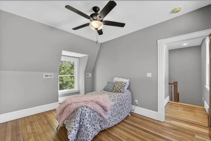 Bedroom with dormer window, ceiling fan, twin bed and doorway to stairs