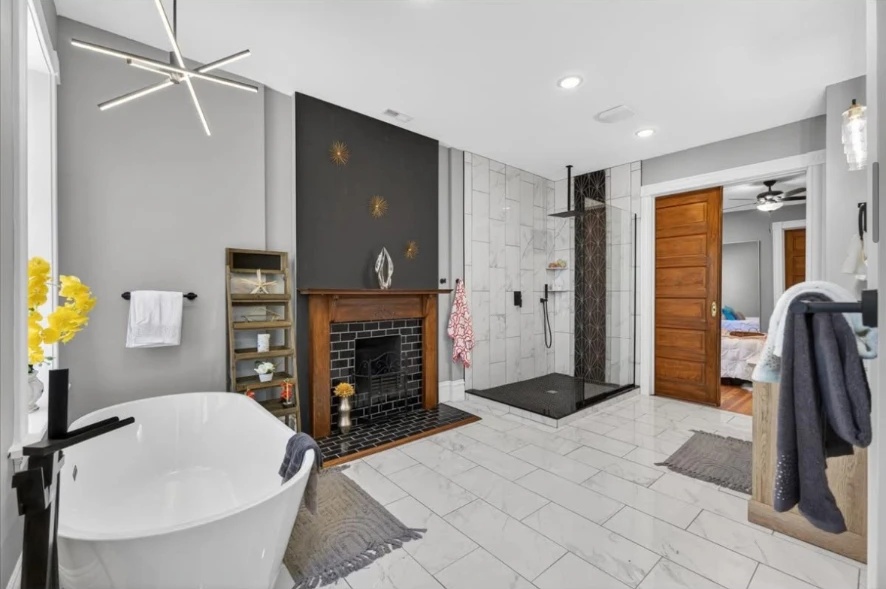 Bathroom with freestanding tub, wood fireplace mantel, tiled shower and paneled wood doorway