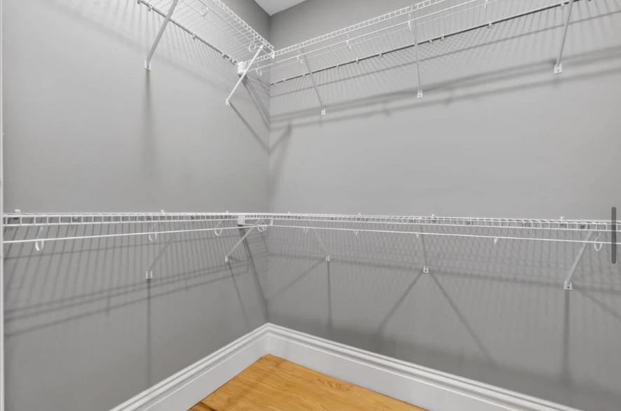 Walk-in closet with white wire shelving, gray walls and wood floor