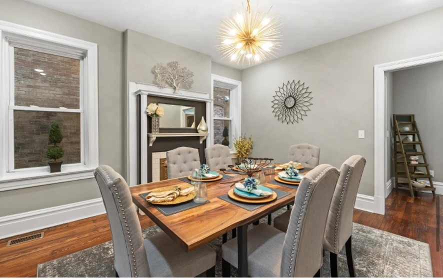 Dining room with wood table, upholstered chairs, dark fireplace mantel and brass starburst chandelier