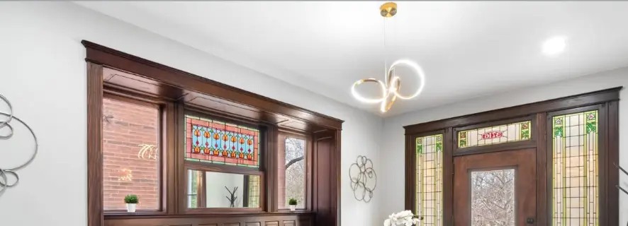 Foyer with dark wood trim, stained glass windows and a modern loop chandelier