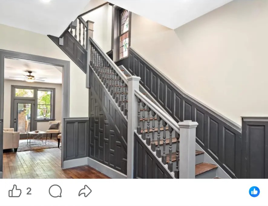 Wood staircase with dark paneled wainscoting, turned balusters and stained glass window