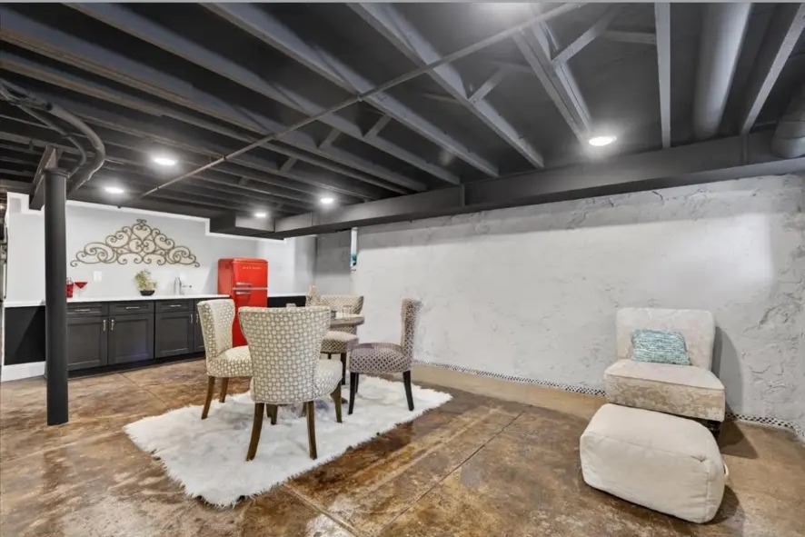 Basement dining table on white rug beside dark cabinetry and a red retro refrigerator