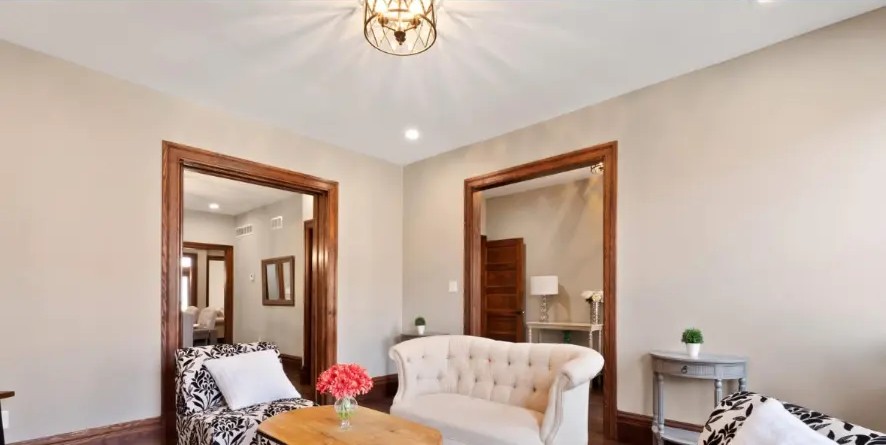 Sitting room with tufted settee, wood-trimmed doorways and warm ceiling light