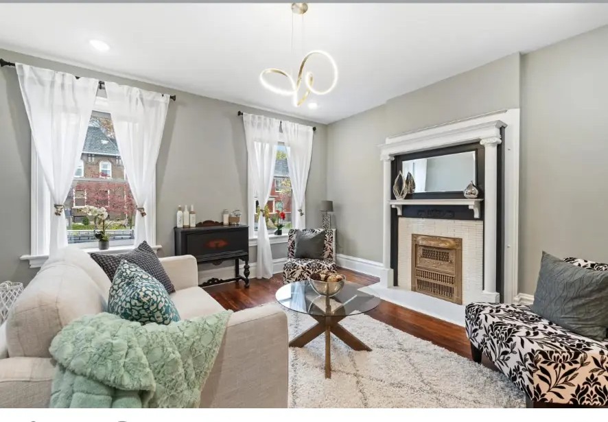 Living room with white fireplace mantel, sheer curtains, sofas and glass coffee table
