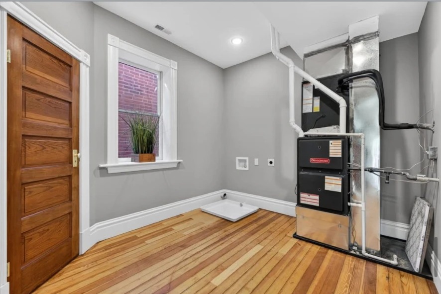 Utility room with wood door, window, furnace system and hardwood floor