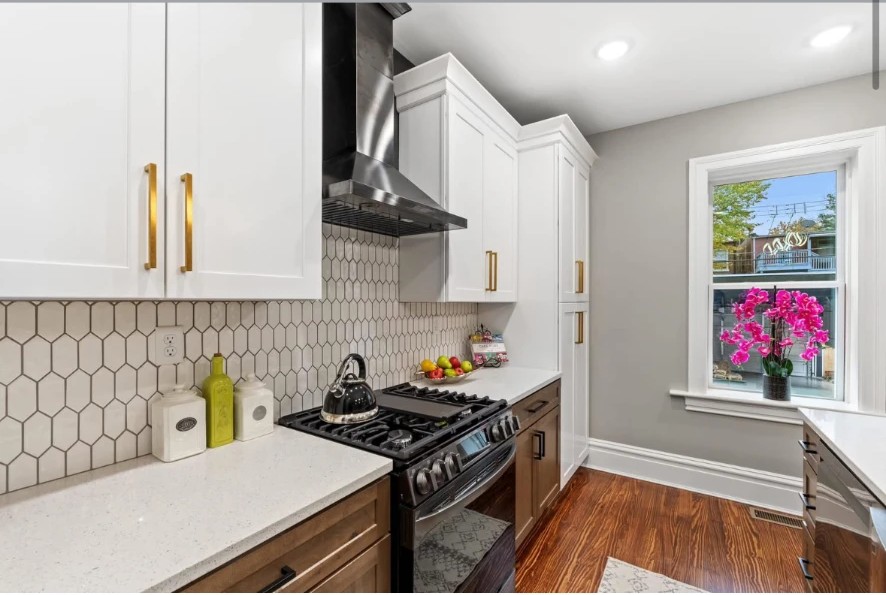Kitchen with stainless range, black hood, hexagonal tile backsplash and wood base cabinets
