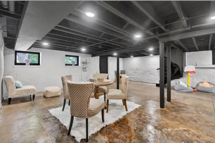 Basement with upholstered dining chairs, armchair, recessed lights and stained concrete floor