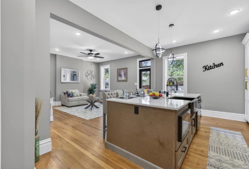 Kitchen island with light countertop and wood cabinetry beside an open living space