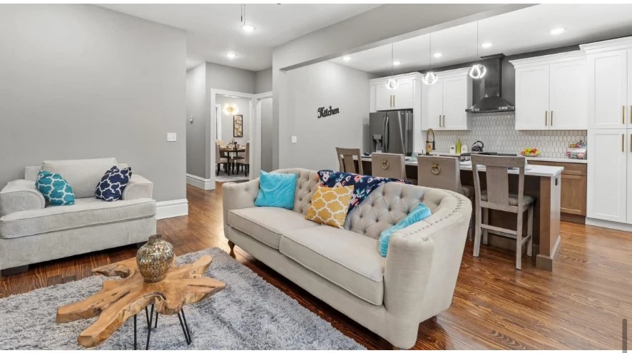 Living room with tufted sofa and turquoise accents opening to a kitchen with island seating