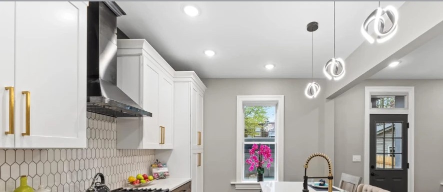 Kitchen with pendant lights, white cabinets and a dark glazed entry door